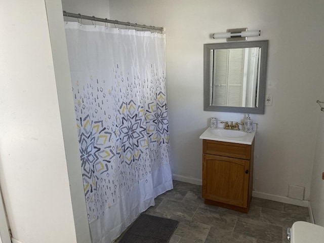 full bathroom featuring stone finish floor, curtained shower, vanity, and baseboards