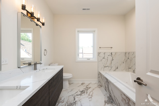 bathroom featuring toilet, vanity, and tiled tub