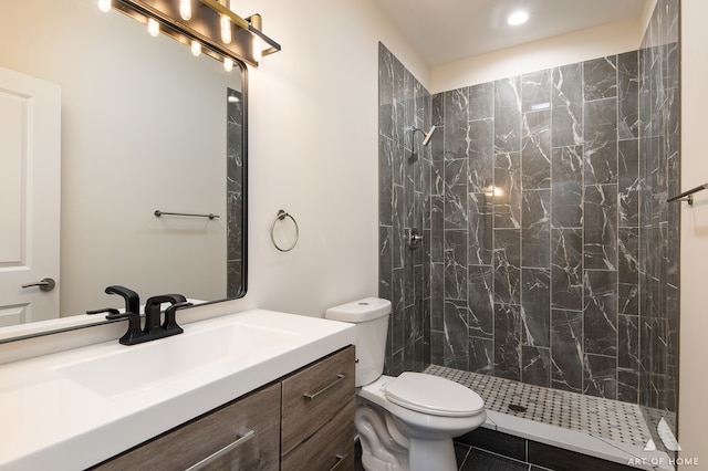 bathroom featuring vanity, a tile shower, toilet, and tile patterned flooring