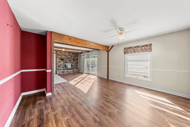 unfurnished living room featuring a fireplace, ceiling fan, dark hardwood / wood-style floors, and brick wall