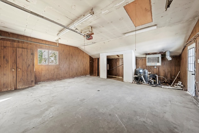 interior space featuring wooden walls, lofted ceiling, and concrete floors