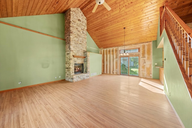 unfurnished living room with wood ceiling, a stone fireplace, light hardwood / wood-style flooring, high vaulted ceiling, and ceiling fan with notable chandelier