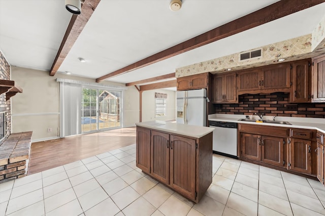 kitchen featuring white refrigerator with ice dispenser, sink, dishwasher, backsplash, and a center island