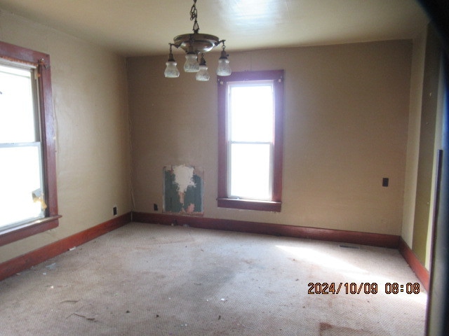 spare room with a chandelier and light colored carpet