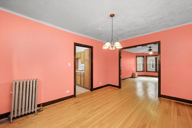 unfurnished room with sink, light hardwood / wood-style flooring, radiator heating unit, and ceiling fan with notable chandelier