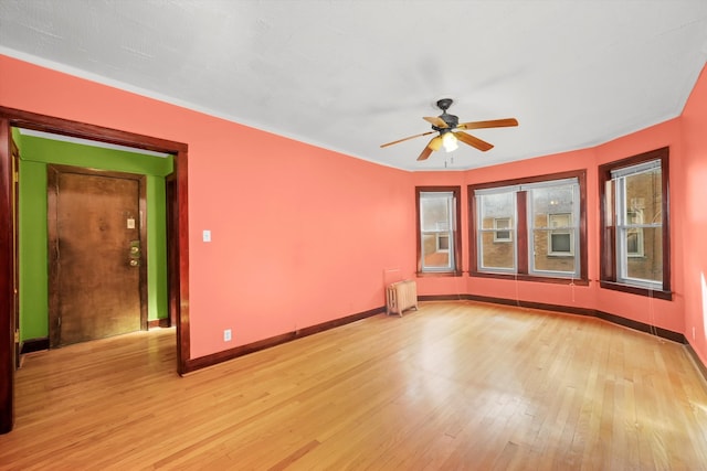 spare room with radiator heating unit, light wood-type flooring, and ceiling fan