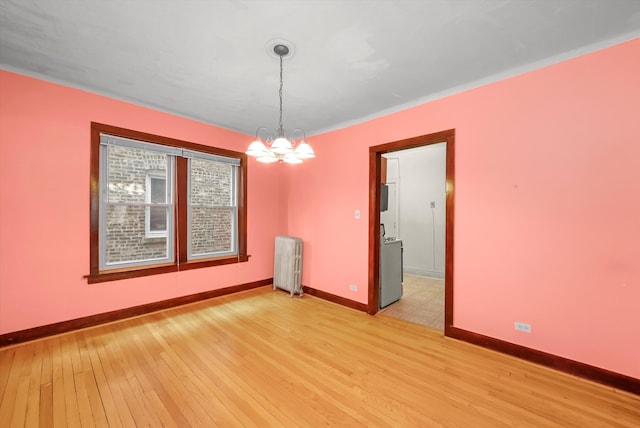 spare room with a chandelier, radiator, and light wood-type flooring