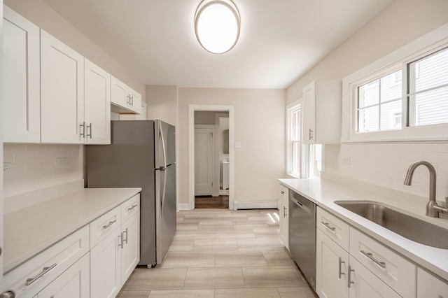 kitchen with white cabinets, sink, tasteful backsplash, a baseboard heating unit, and appliances with stainless steel finishes