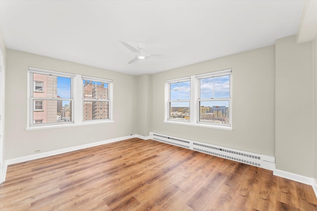 empty room featuring ceiling fan, wood-type flooring, and a baseboard radiator