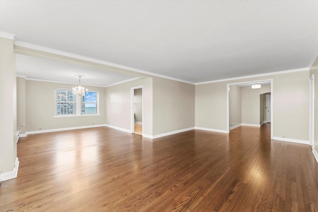 spare room with a notable chandelier, ornamental molding, and dark wood-type flooring