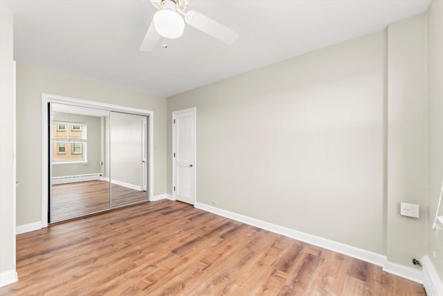 unfurnished bedroom featuring ceiling fan, light hardwood / wood-style floors, a closet, and a baseboard heating unit