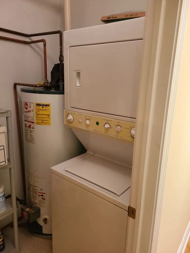 laundry area with stacked washer / drying machine and water heater