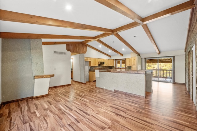 unfurnished living room with vaulted ceiling with beams and light hardwood / wood-style floors