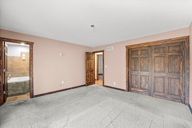 unfurnished bedroom with ensuite bath and light colored carpet