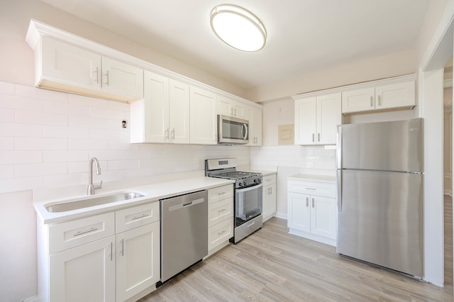 kitchen with a sink, stainless steel appliances, light countertops, and white cabinetry