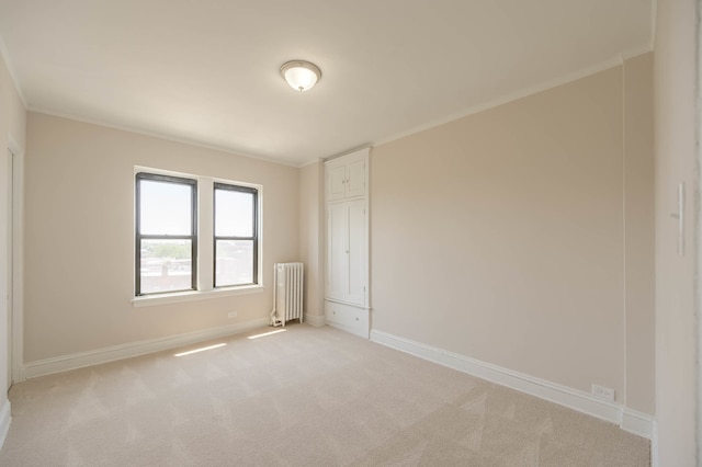 empty room with radiator heating unit, ornamental molding, baseboards, and light colored carpet