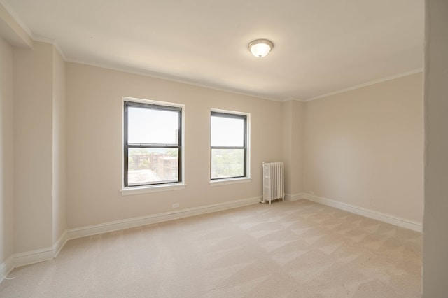 spare room featuring light carpet, radiator heating unit, baseboards, and crown molding