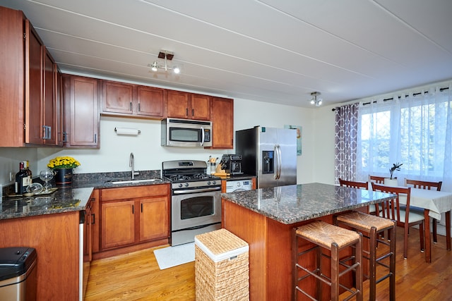 kitchen featuring stainless steel appliances, light hardwood / wood-style flooring, a kitchen island, and sink