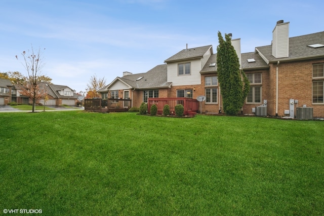 view of yard with a garage, a wooden deck, and central AC