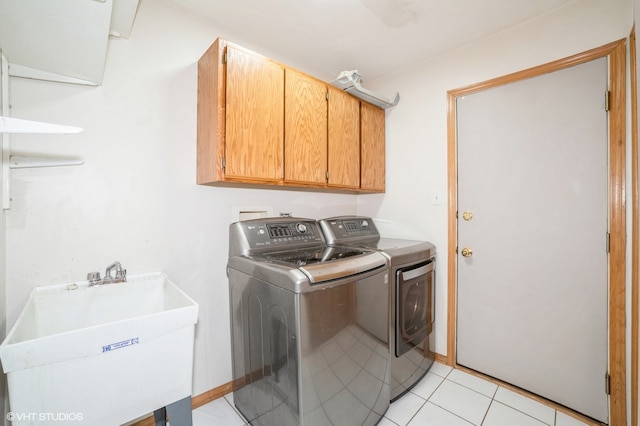 laundry room featuring independent washer and dryer, cabinets, sink, and light tile patterned flooring