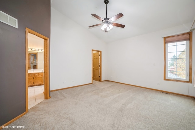 unfurnished bedroom with ensuite bath, ceiling fan, high vaulted ceiling, light colored carpet, and a closet