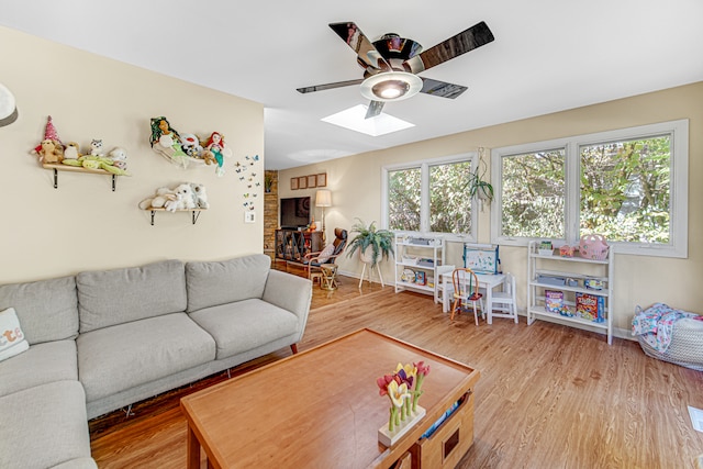 living room featuring a skylight, ceiling fan, and wood-type flooring