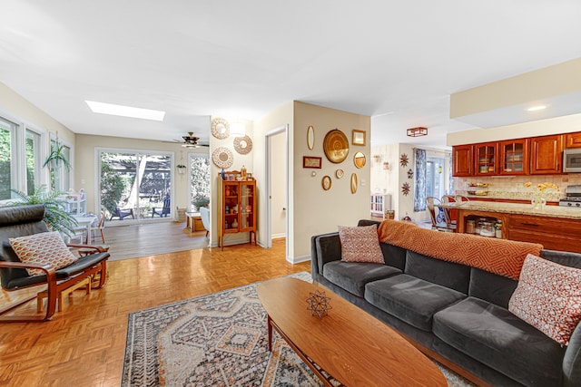 living room with light parquet flooring, a skylight, and ceiling fan