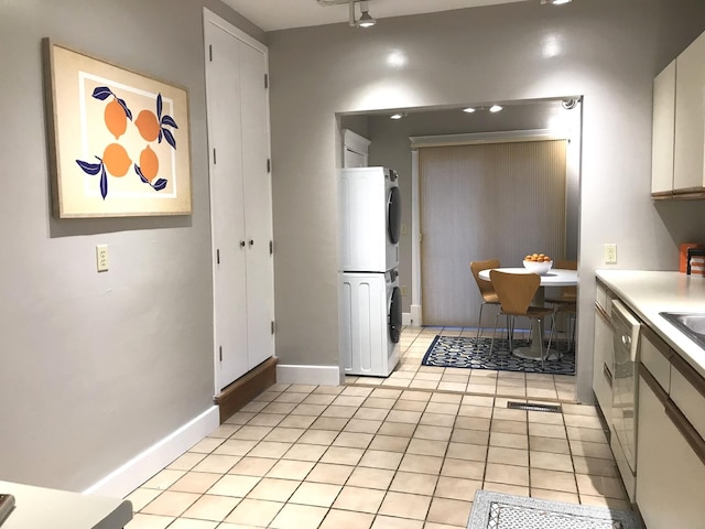 kitchen featuring dishwasher, stacked washer and dryer, and light tile patterned floors