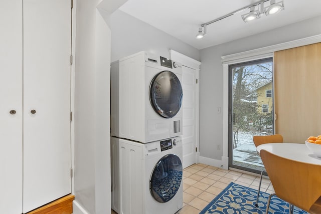 laundry area with light tile patterned floors and stacked washer and dryer