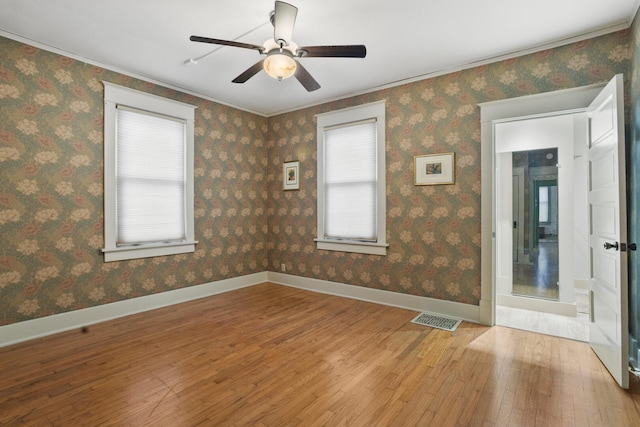 empty room featuring hardwood / wood-style floors, ceiling fan, plenty of natural light, and ornamental molding