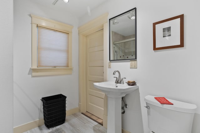 bathroom with a shower with door and toilet