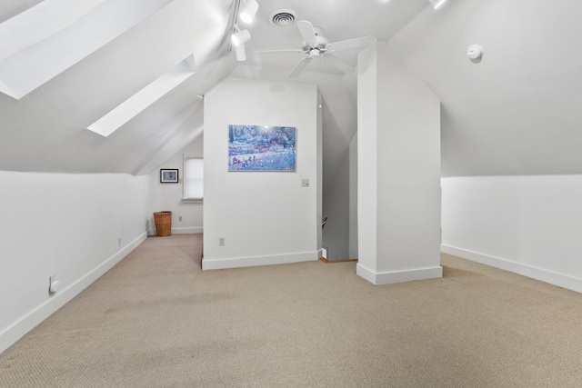 additional living space featuring light colored carpet, ceiling fan, and vaulted ceiling with skylight