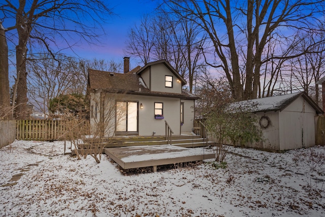 snow covered house featuring a wooden deck and a shed