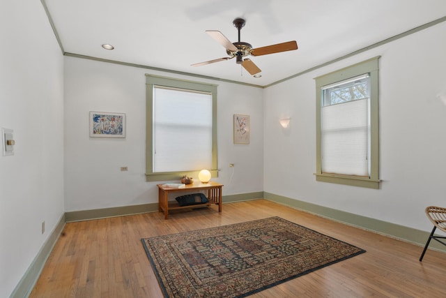 sitting room with ceiling fan, light wood-type flooring, and ornamental molding