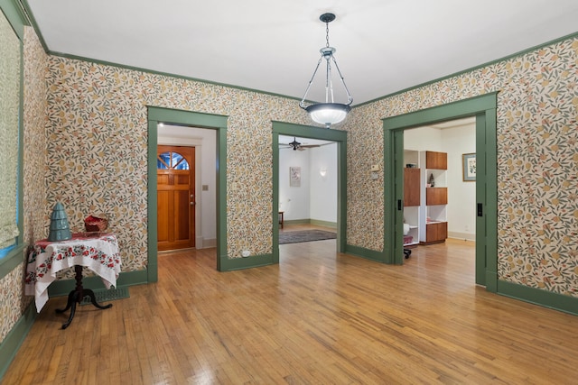 interior space with ceiling fan, wood-type flooring, and crown molding