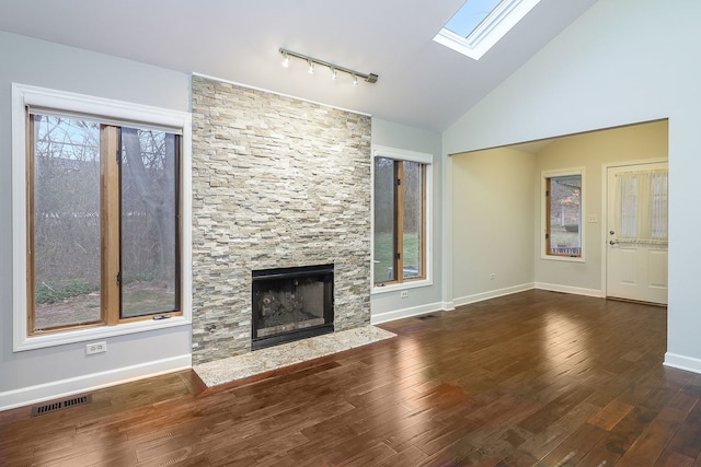 unfurnished living room featuring a stone fireplace, a wealth of natural light, and dark hardwood / wood-style floors