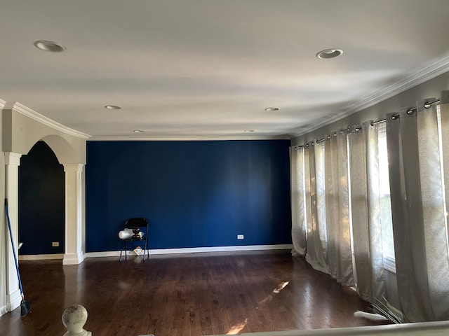 spare room with crown molding, dark hardwood / wood-style floors, and decorative columns