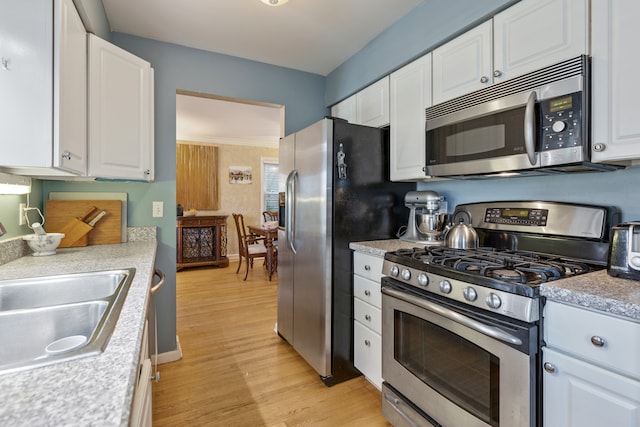 kitchen with white cabinetry, light hardwood / wood-style floors, stainless steel appliances, and sink