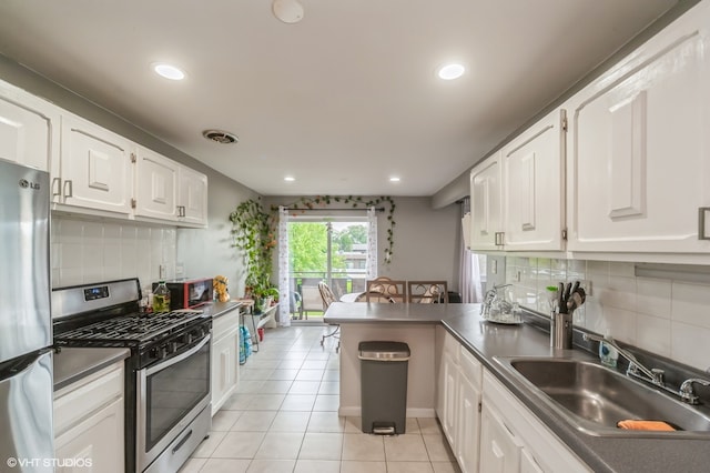 kitchen with decorative backsplash, kitchen peninsula, stainless steel appliances, sink, and white cabinets