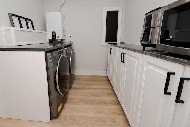 clothes washing area featuring washing machine and dryer, tankless water heater, and light hardwood / wood-style floors