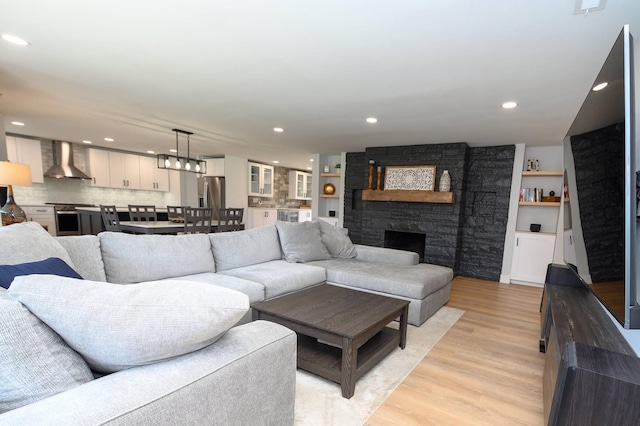 living room featuring a stone fireplace and light wood-type flooring