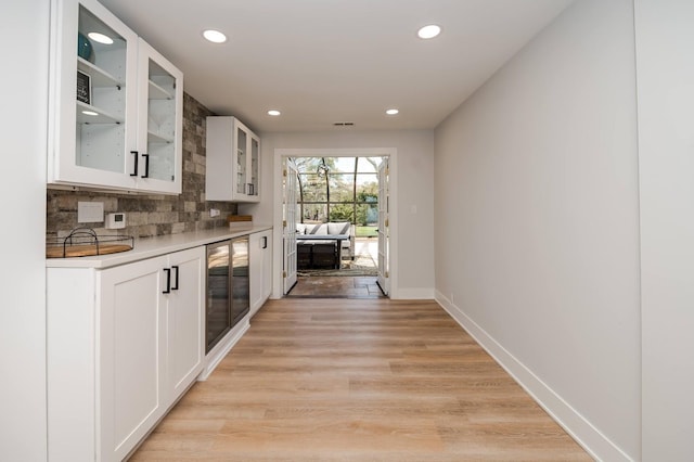 kitchen with decorative backsplash, light hardwood / wood-style floors, beverage cooler, and white cabinets