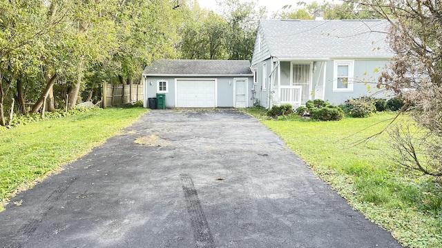view of front of house featuring a front lawn, aphalt driveway, a shingled roof, fence, and a garage