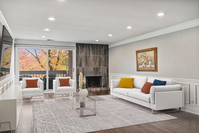 living room featuring crown molding, a large fireplace, and hardwood / wood-style floors