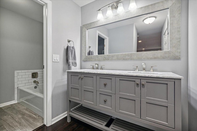 bathroom with hardwood / wood-style flooring, vanity, and a tub