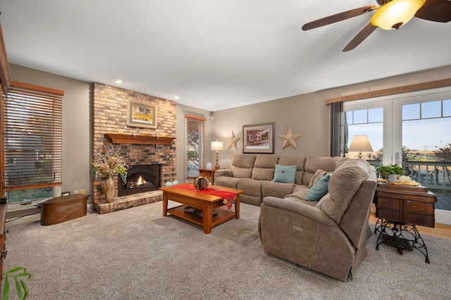 carpeted living room with a brick fireplace and ceiling fan