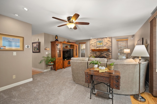 carpeted living room with a fireplace and ceiling fan