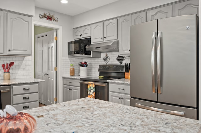 kitchen featuring stainless steel appliances, gray cabinets, backsplash, and light stone counters