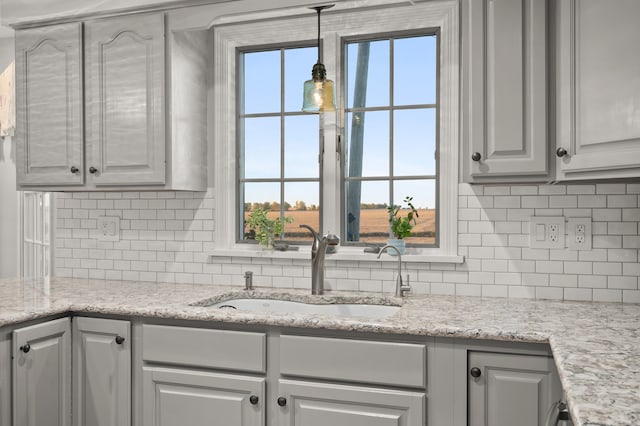 kitchen featuring pendant lighting, sink, light stone counters, and plenty of natural light