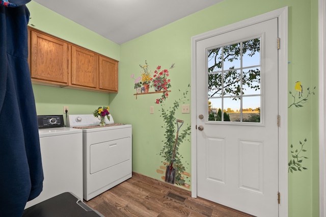 clothes washing area featuring cabinets, dark hardwood / wood-style floors, and washing machine and clothes dryer